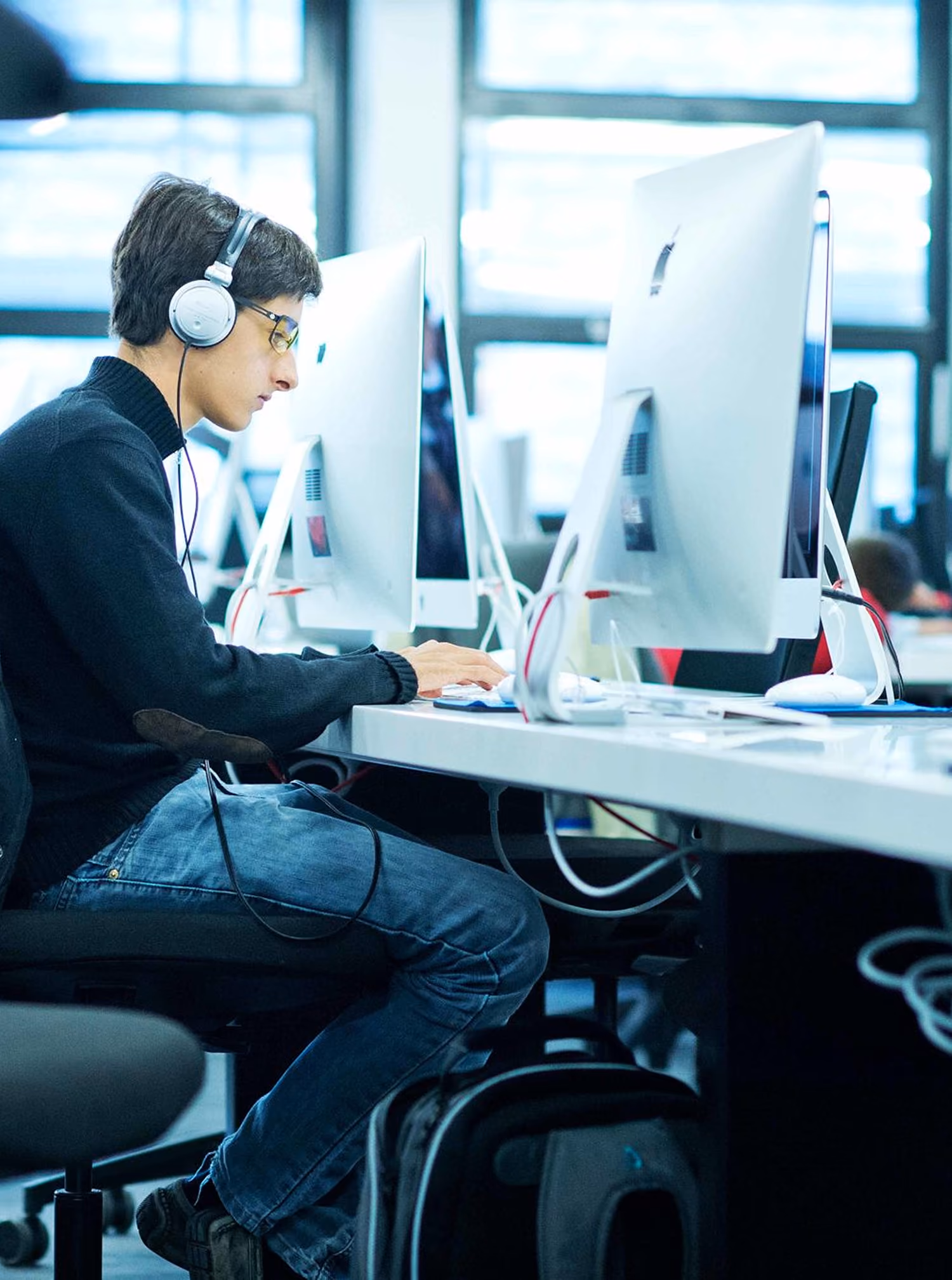 Étudiant de l'école 42 travaillant sur un ordinateur, casque sur les oreilles