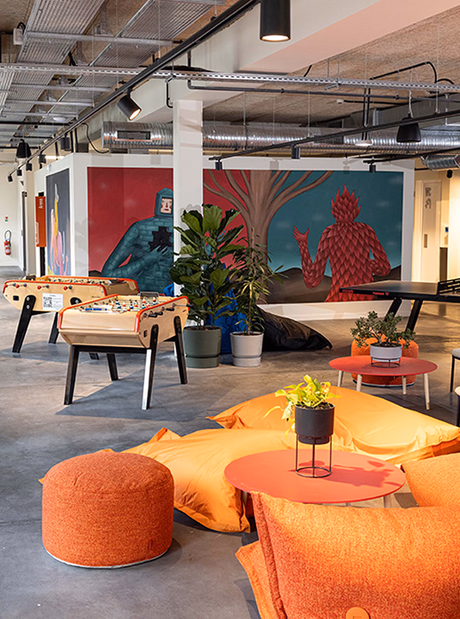 Espace de détente de l'école 42 avec des poufs orange et un babyfoot