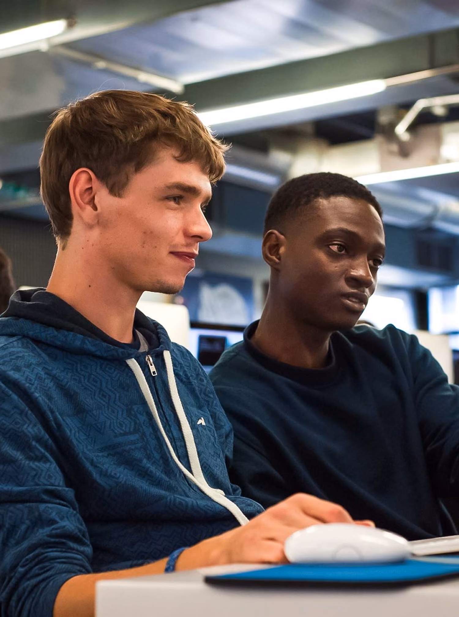 Deux étudiants de l'école 42 souriant devant un ordinateur